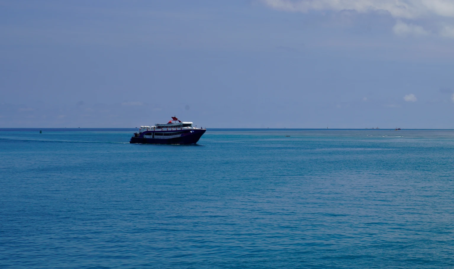 A blue and white Songserm ferry crossing the calm turquoise Gulf of Thailand off Koh Phangan